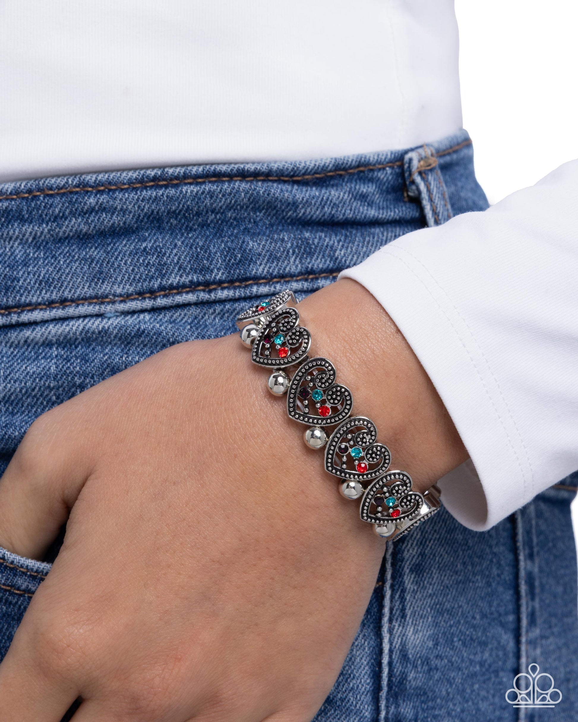 Silver bracelet with colorful beads on a wrist against a white shirt and blue jeans background