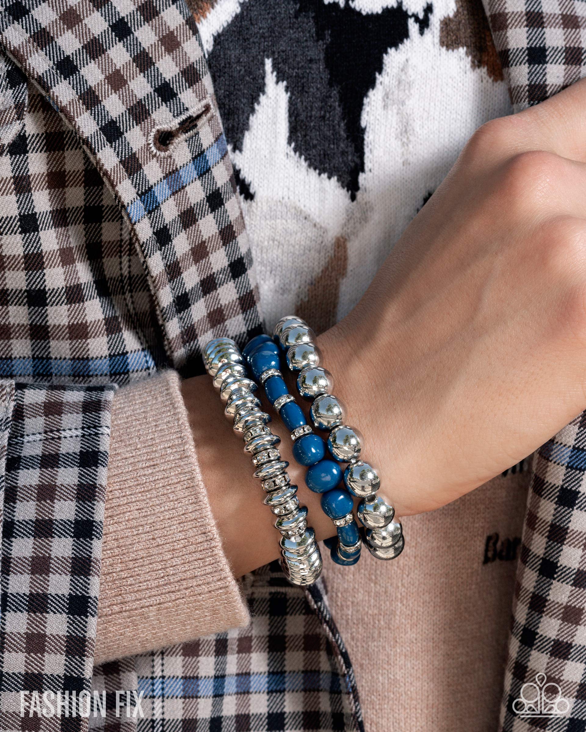 Close-up of a person wearing blue and silver beaded bracelets on a plaid shirt background.