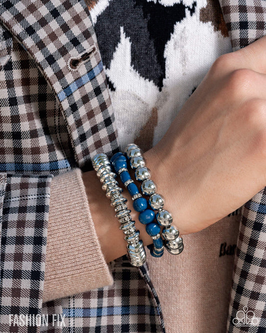 Close-up of a person wearing blue and silver beaded bracelets on a plaid shirt background.