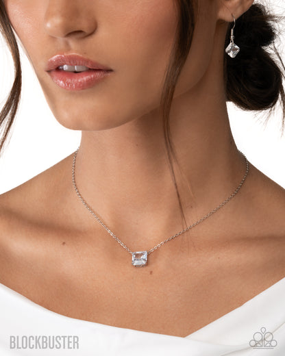 Close-up of a woman wearing a silver necklace with a clear pendant on a white background.