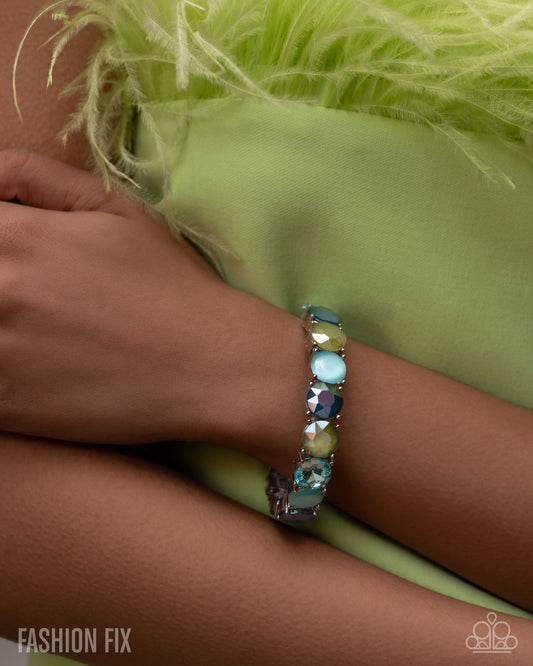 Bracelet with multicolored stones on a wrist against a green fabric background