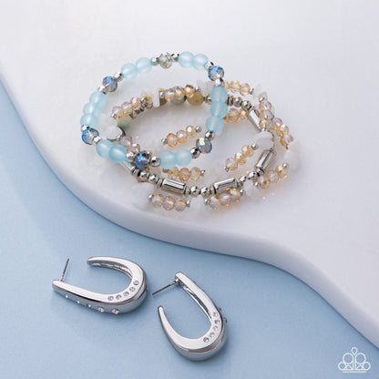 Beaded bracelet and silver hoop earrings on a light blue background