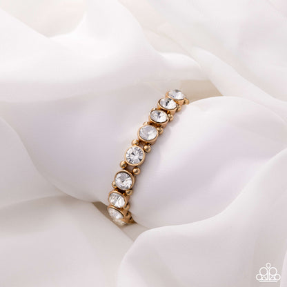 Gold bracelet with clear stones on a white fabric background