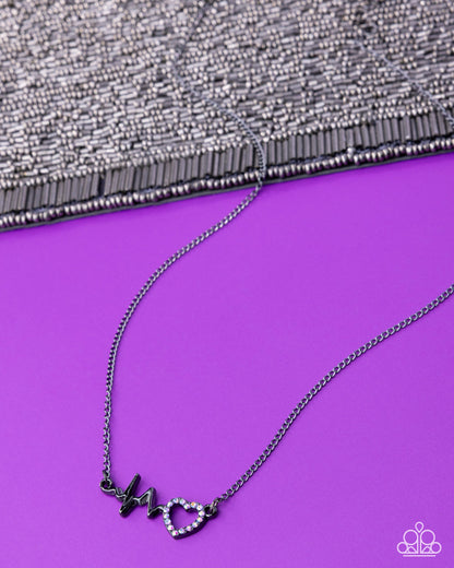 Necklace with heart and lightning bolt pendant on a purple surface