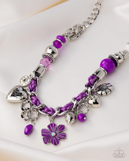 Purple beaded bracelet with silver charms on a white background