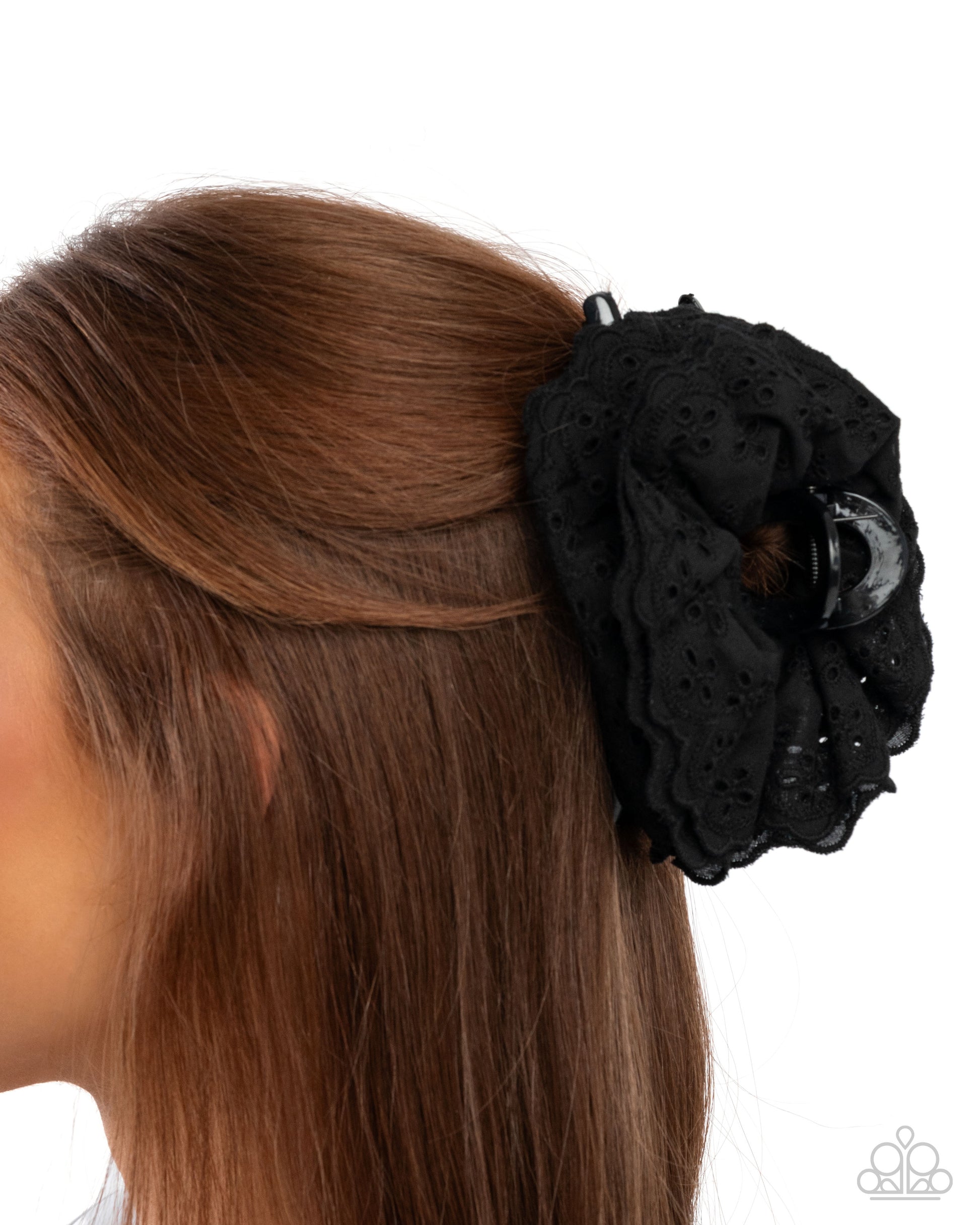 Black floral hair accessory on a person with brown hair against a white background