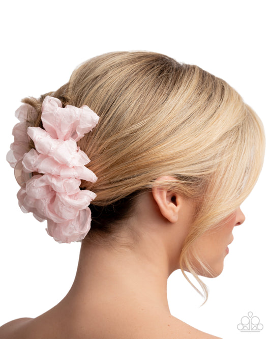 Pink scrunchie in a blonde hair bun on a white background