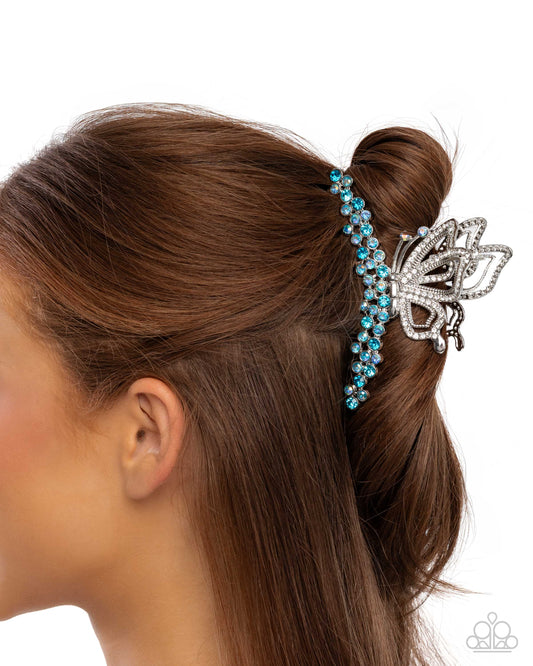 Woman with brown hair styled in a bun with a decorative blue and silver hair accessory.