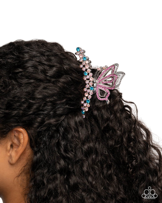 Pink butterfly hair clip on black hair against a white background