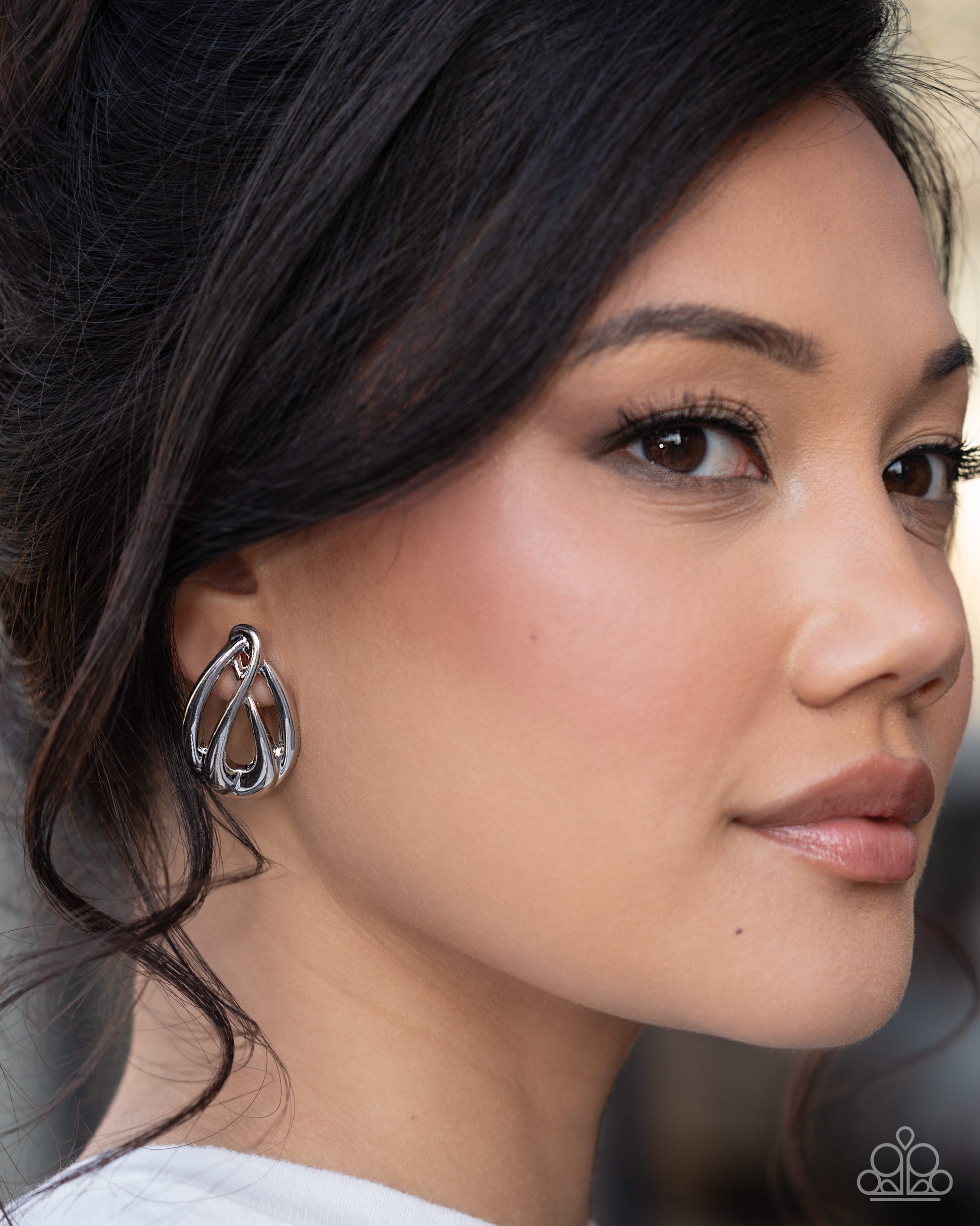 Close-up of a woman wearing a silver hoop earring with a blurred background