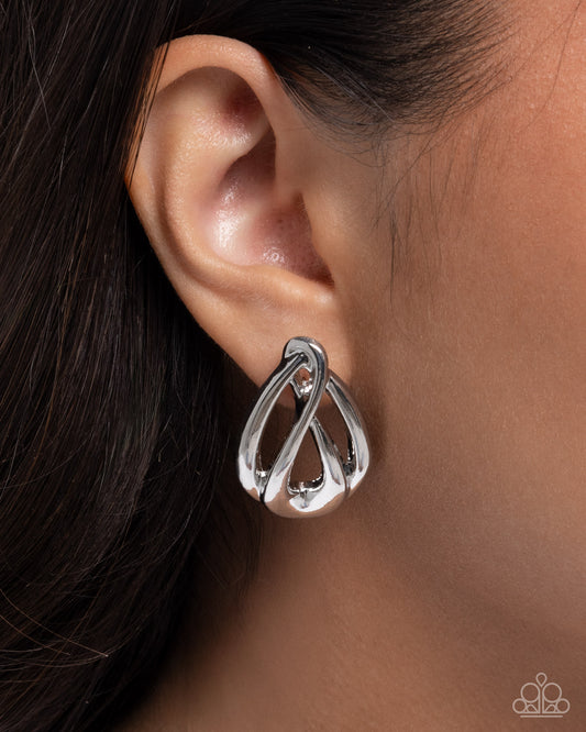 Silver earring worn on an ear with dark hair and skin background