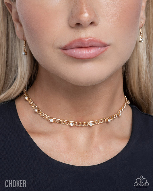 Close-up of a woman wearing a gold chain choker necklace with small gemstones.