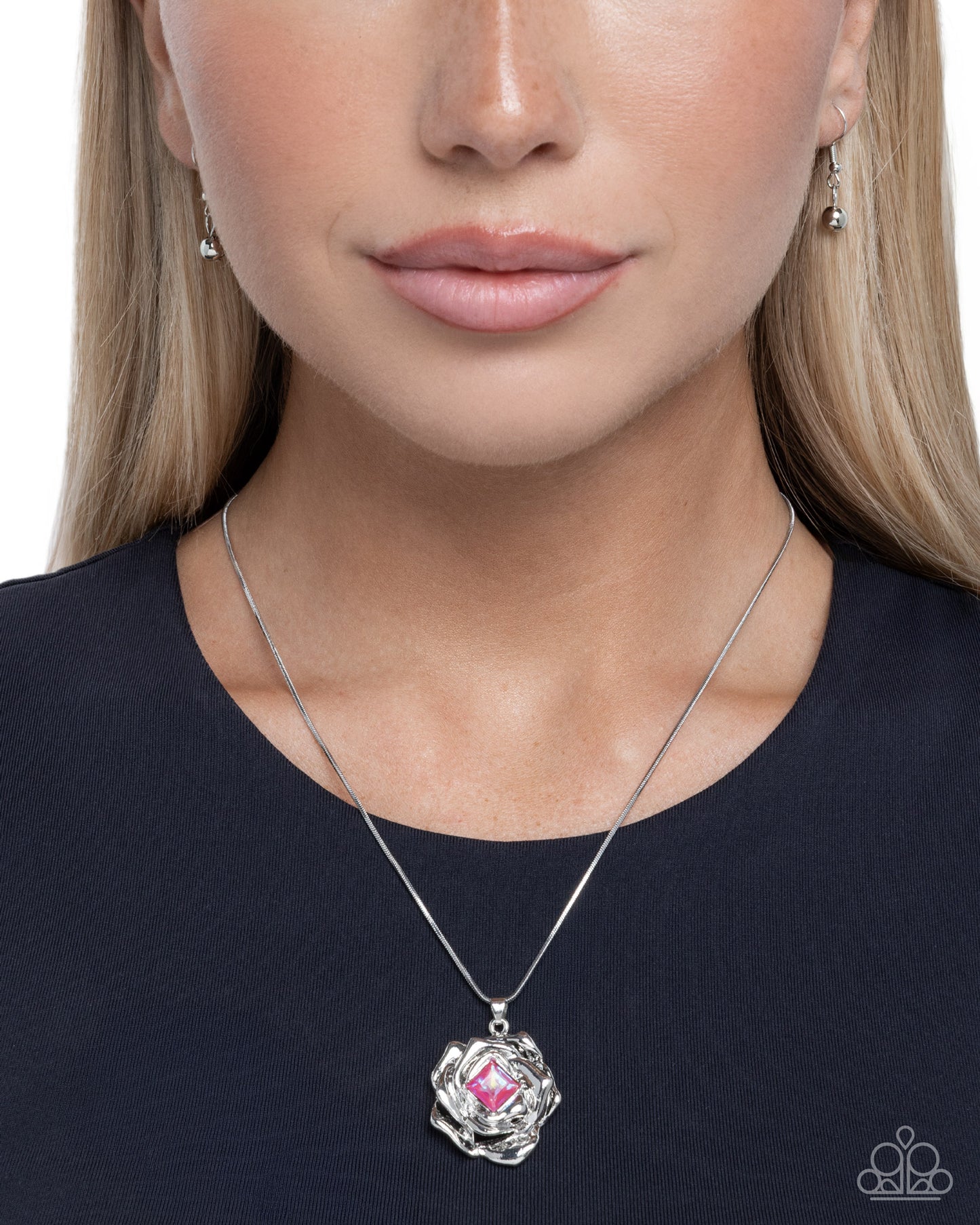 Woman wearing a silver necklace with a pink pendant on a white background