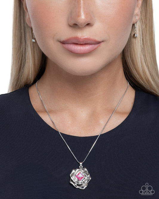 Woman wearing a silver necklace with a pink pendant on a white background