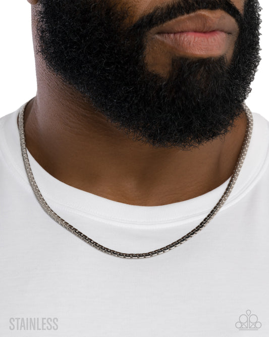 Close-up of a person wearing a silver chain necklace on a white background