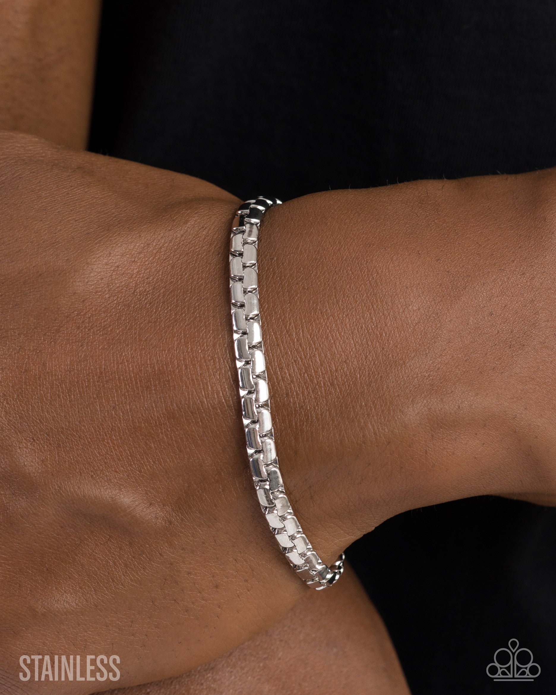Silver bracelet on a wrist with a dark background