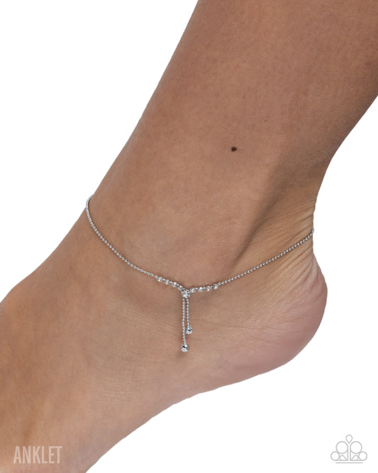 A delicate silver anklet with a Y-shaped drop charm, shown worn on a person's ankle against a white background.