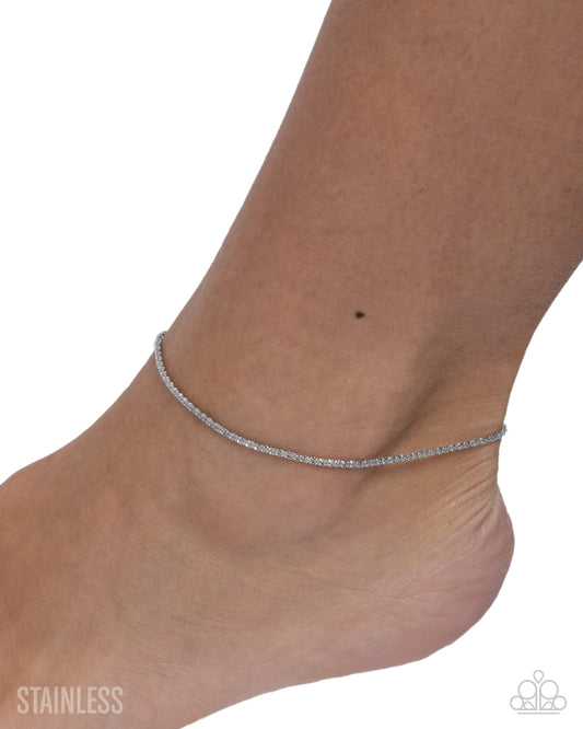Silver anklet on a foot with 'Stainless' text