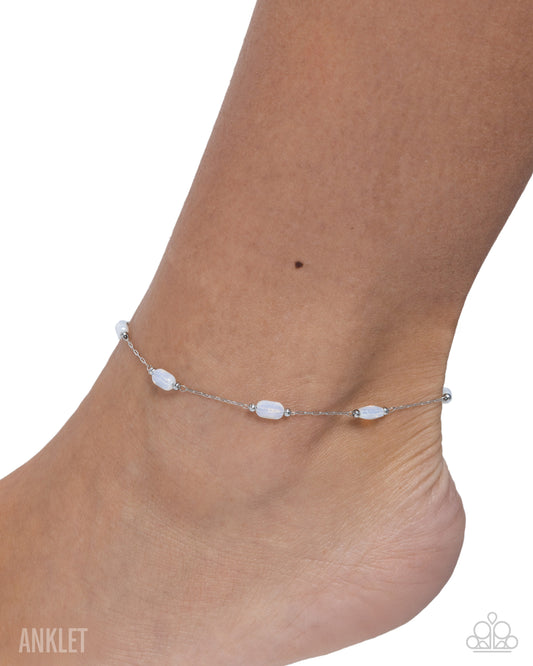 Silver anklet on a foot against a white background