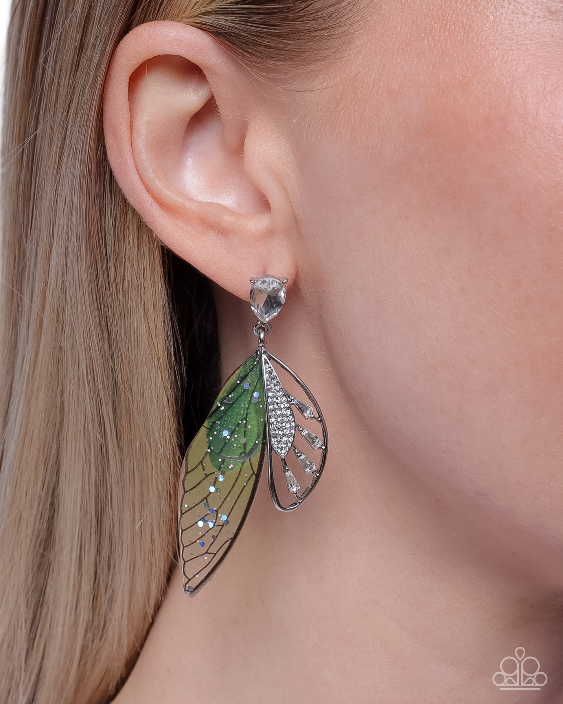 Close-up of a person wearing a green leaf-shaped earring with a clear gemstone.