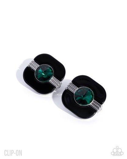 A pair of pop-art style cufflinks featuring a glossy black enamel background, a central round green faceted crystal, and silver-tone striped accents, shown on a clean white background.