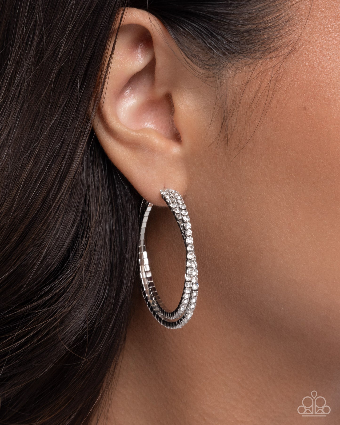 Silver hoop earrings worn by a person with dark hair.
