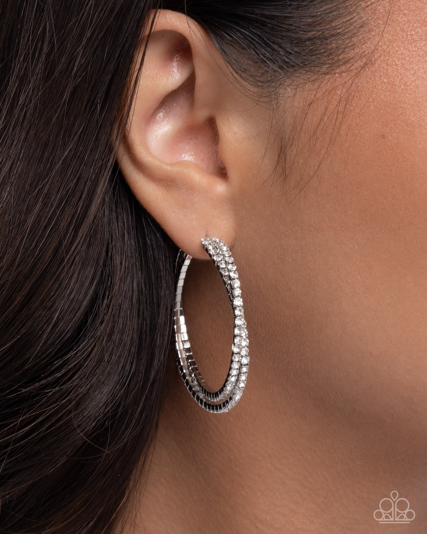 Silver hoop earrings worn by a person with dark hair.