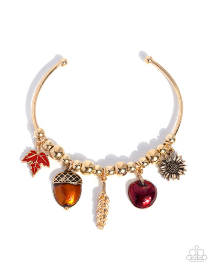 Gold necklace with autumn-themed charms on a white background