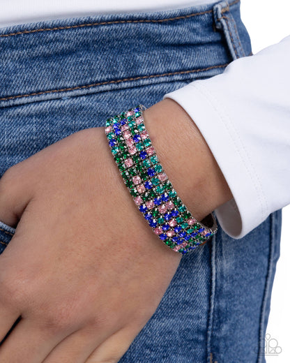 Multicolored beaded bracelet on a wrist with denim jeans and a white sleeve in the background