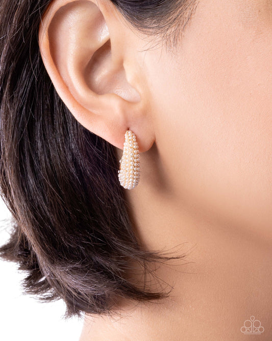 Close-up of an ear wearing a pearl earring with a blurred background