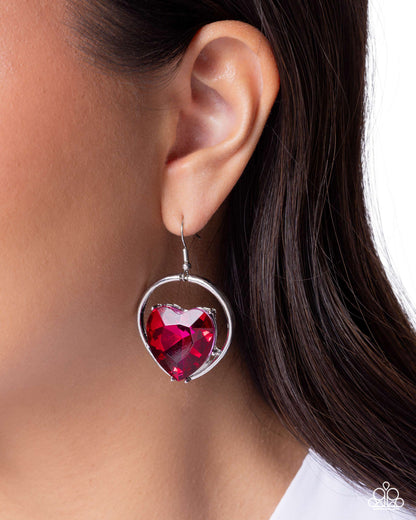 Earring with a red heart-shaped gemstone worn by a person