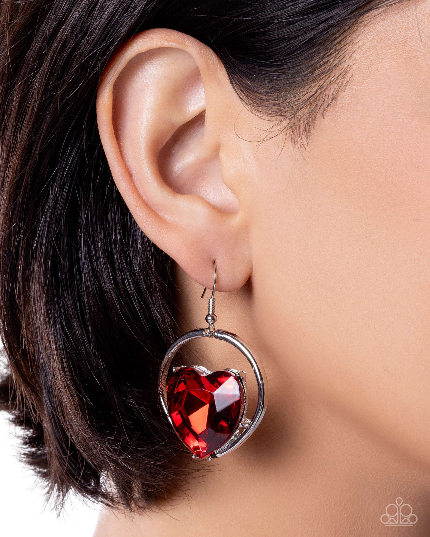 Red heart-shaped earring worn by a person with dark hair.