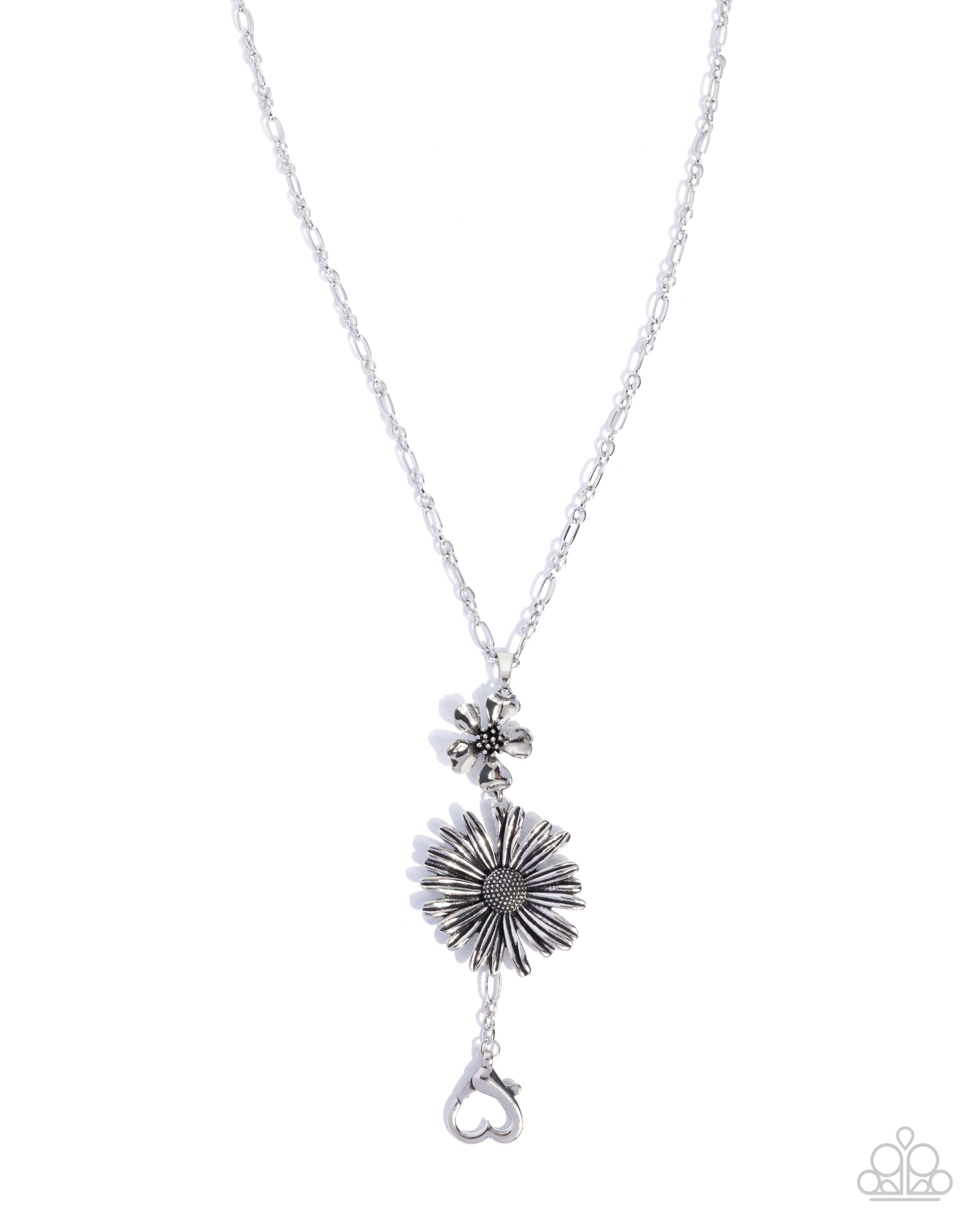 Silver necklace with a starburst pendant and heart charm on a white background