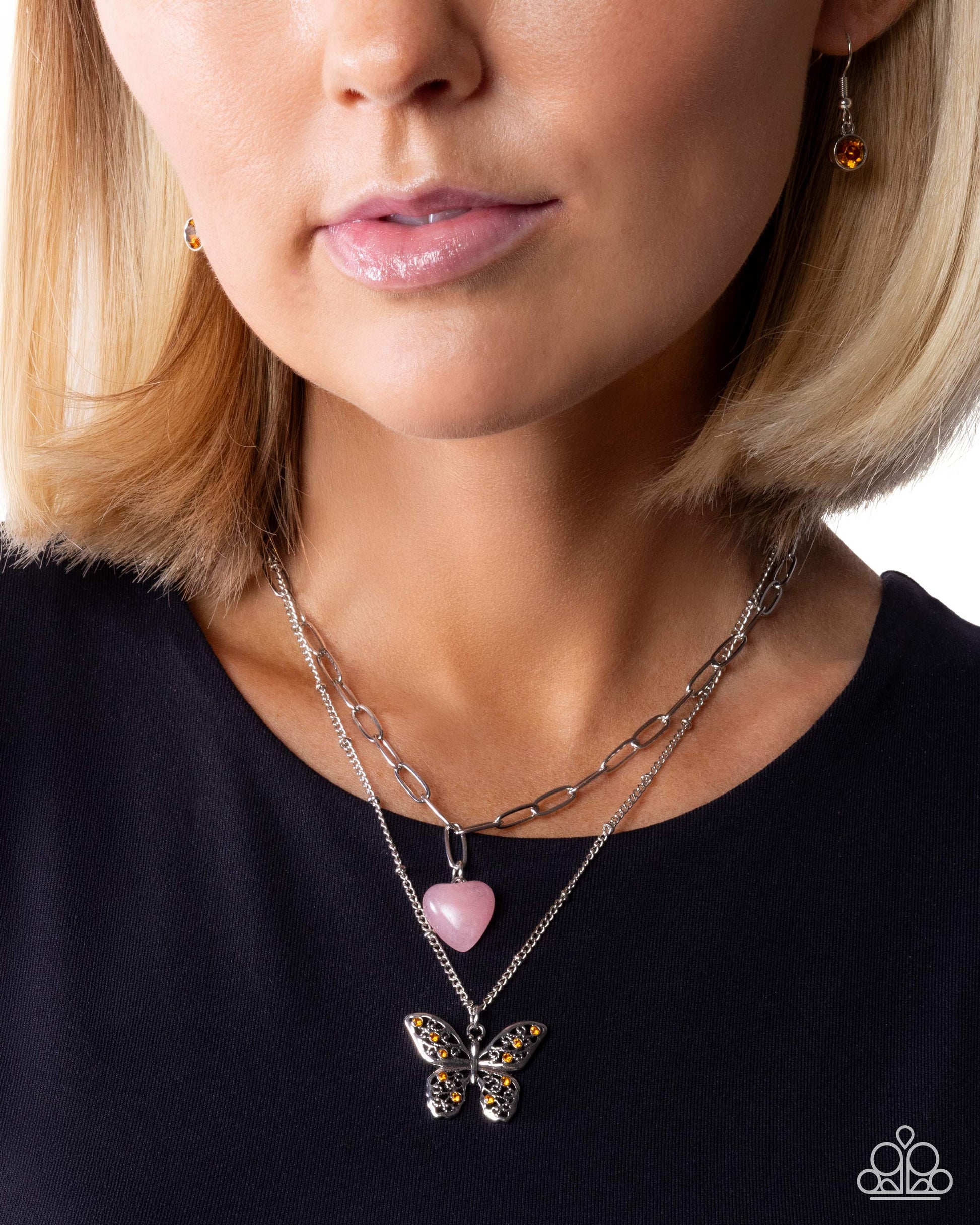 Close-up of a woman wearing a butterfly pendant necklace on a plain background