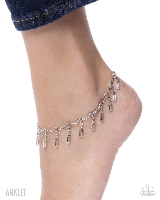 Silver anklet on a foot against a white background