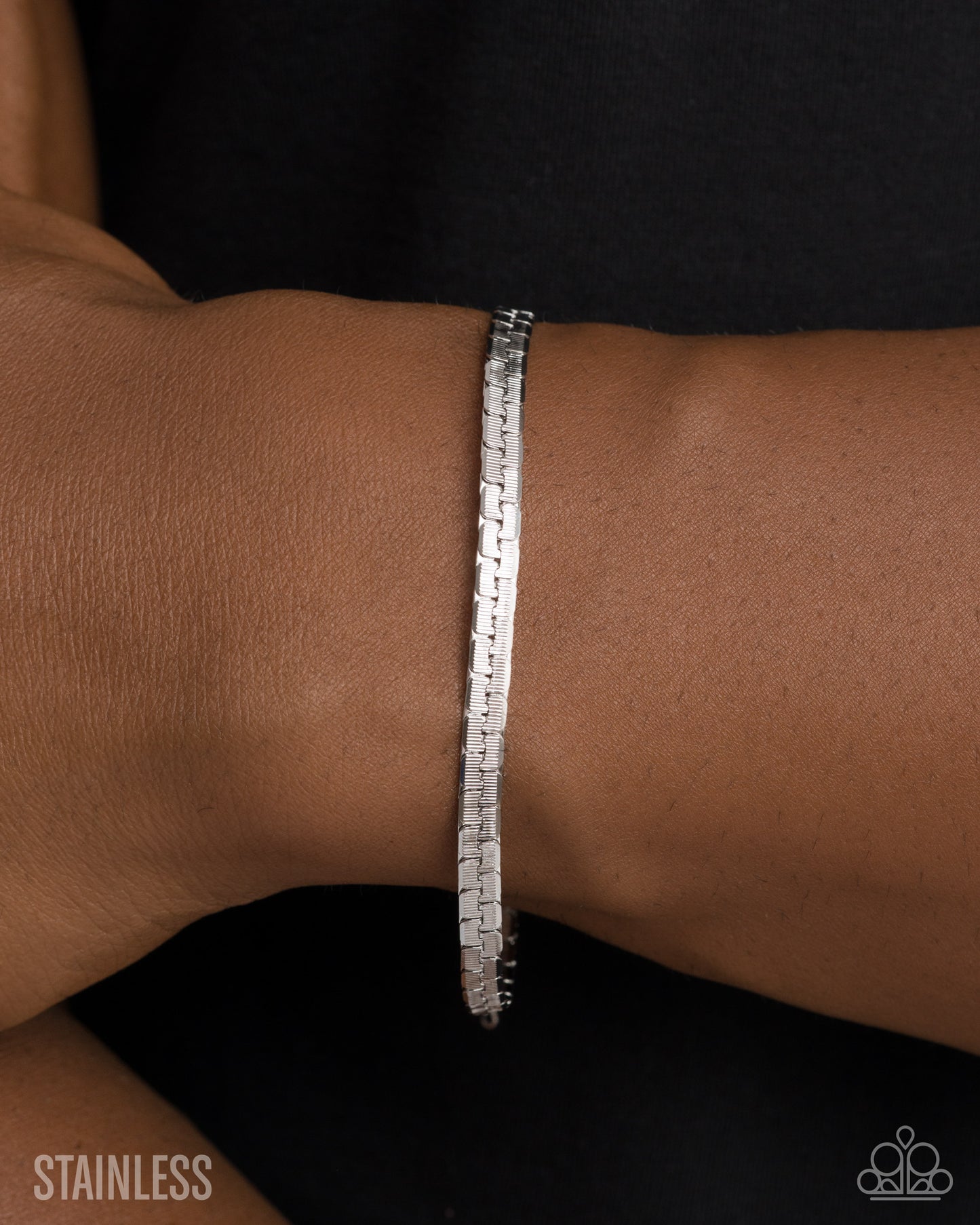 Silver bracelet on a wrist with 'Stainless' text