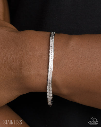 Silver bracelet on a wrist with 'Stainless' text