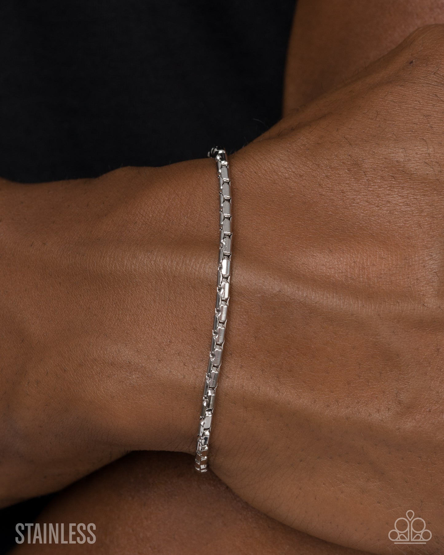 Silver bracelet on a wrist with 'Stainless' text
