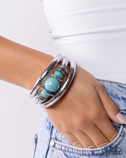 Silver bracelet with turquoise beads on a wrist against a white background