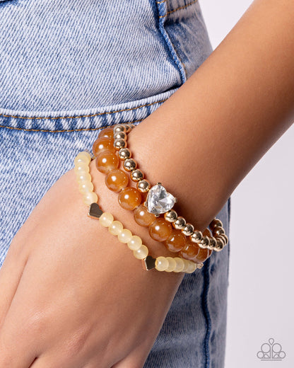 Close-up of a wrist wearing multiple beaded bracelets with a denim background
