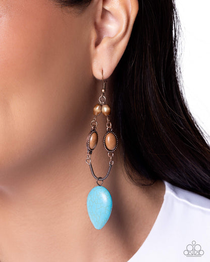 Turquoise teardrop earring worn by a model with a blurred background