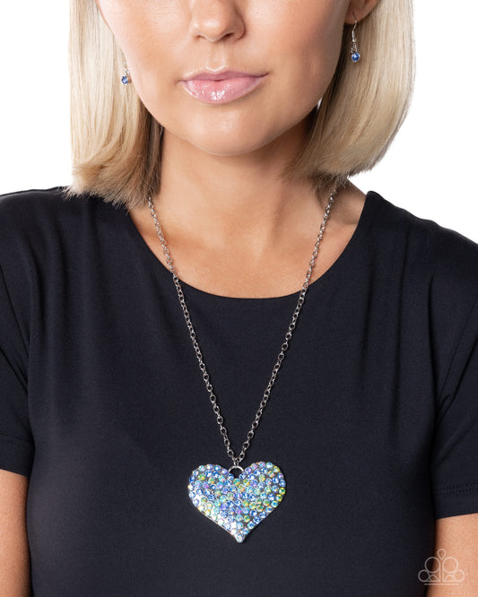 Woman wearing a black shirt with a colorful heart-shaped pendant necklace.