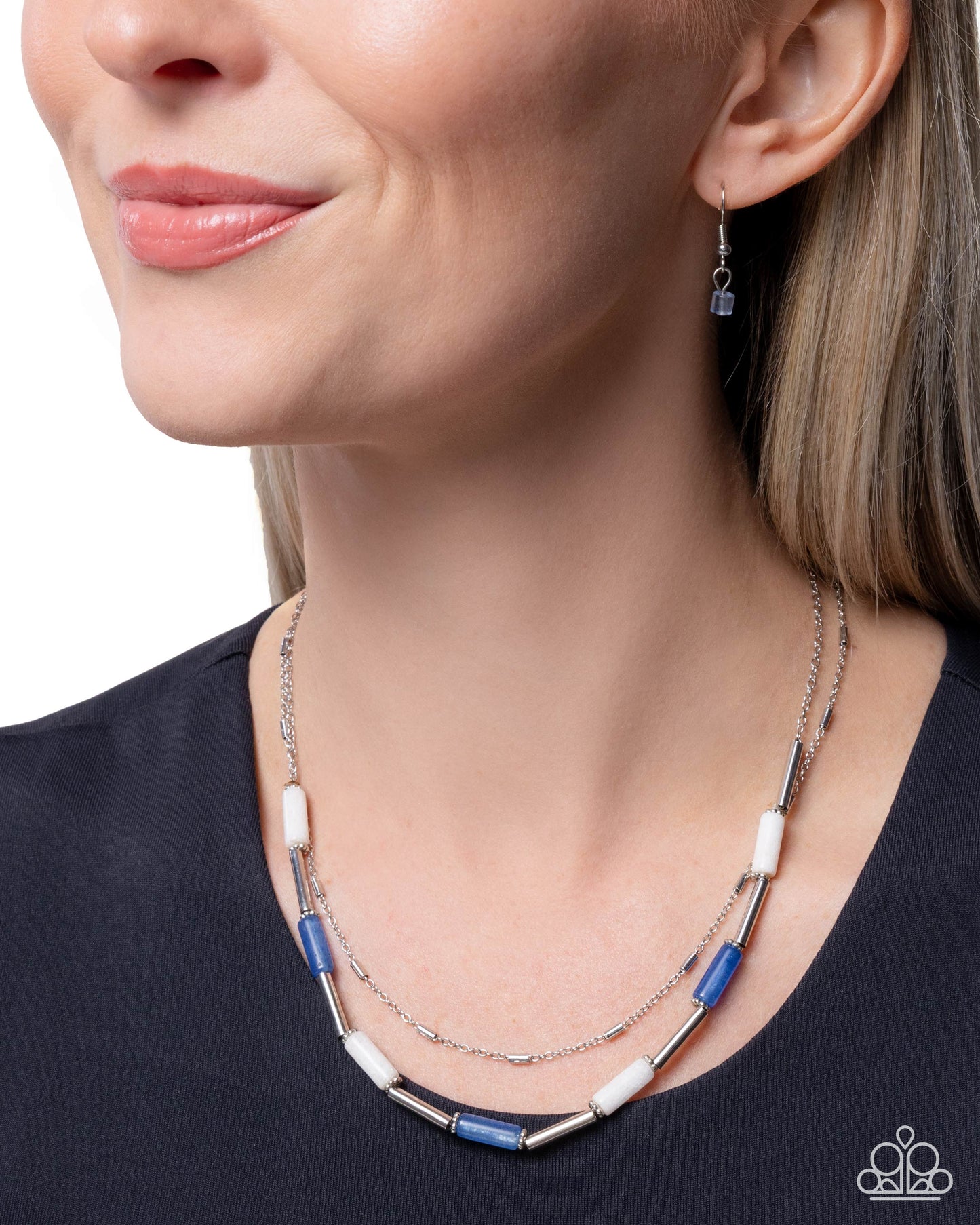 Woman wearing a layered necklace with blue and white beads on a plain background