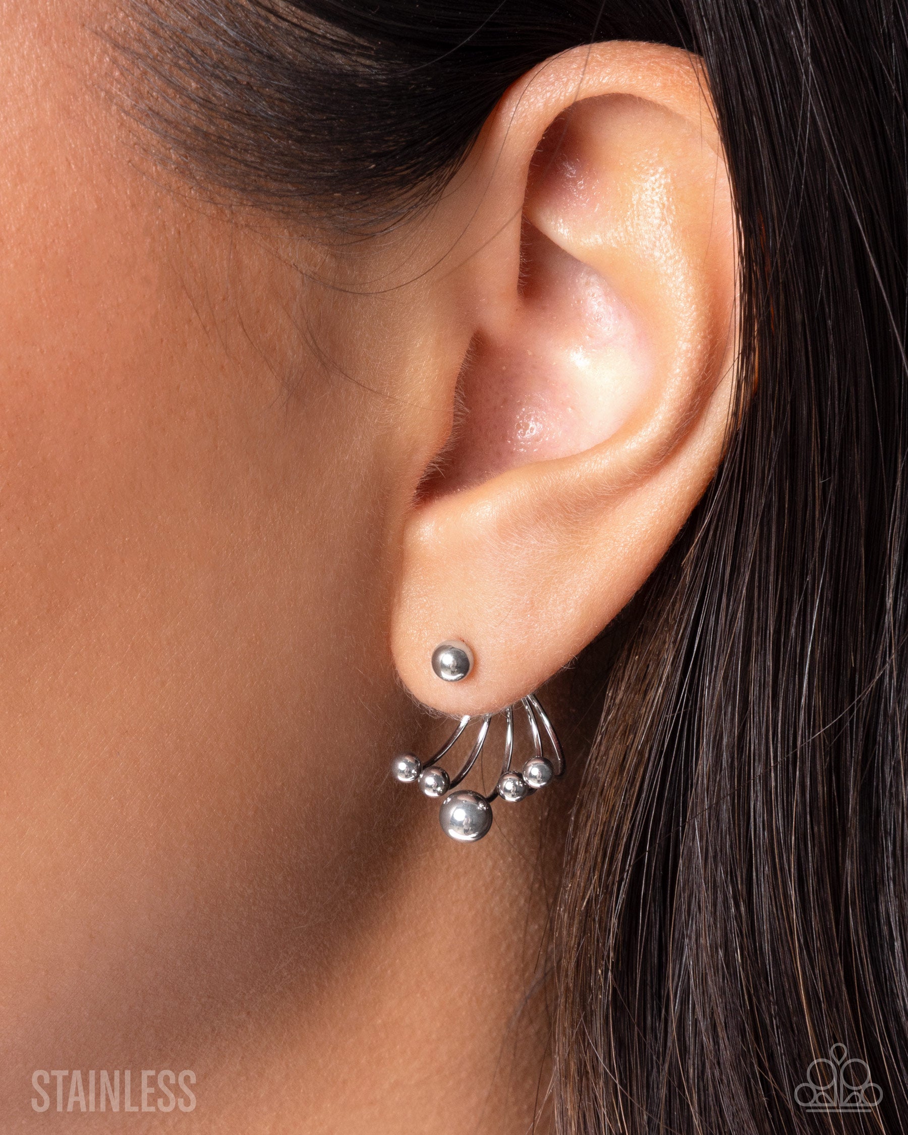 Close-up of an ear wearing a silver earring with beads.