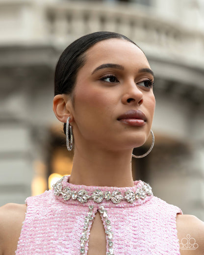 Woman wearing a pink dress with intricate detailing in an outdoor setting