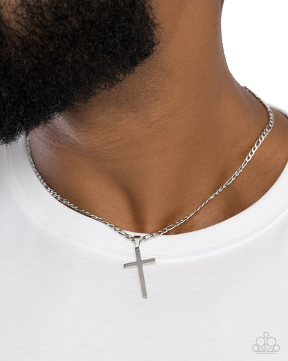 Silver cross necklace on a person wearing a white shirt