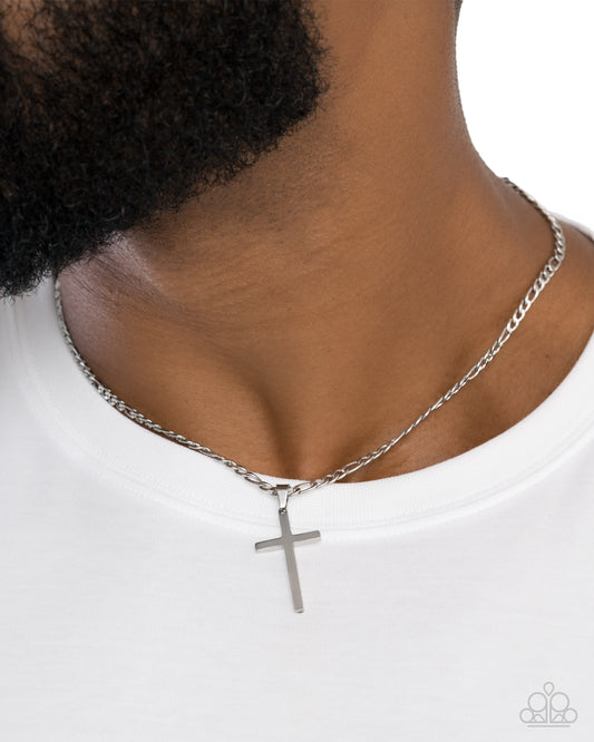 Silver cross necklace on a person wearing a white shirt