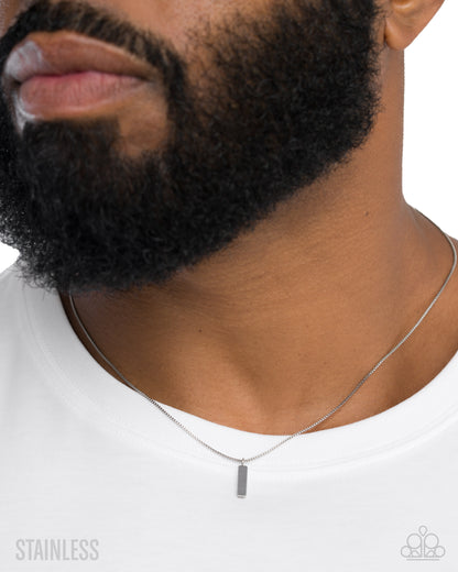 Man wearing a silver necklace with a pendant on a white background