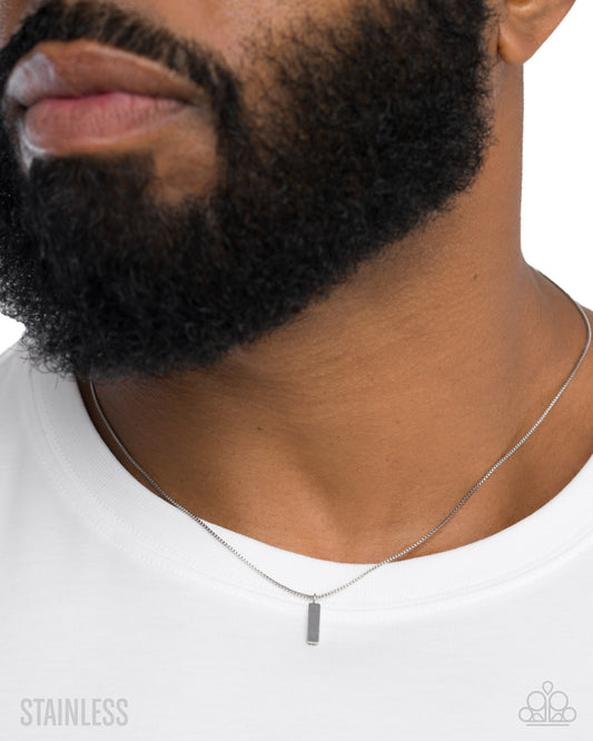 Man wearing a silver necklace with a pendant on a white background