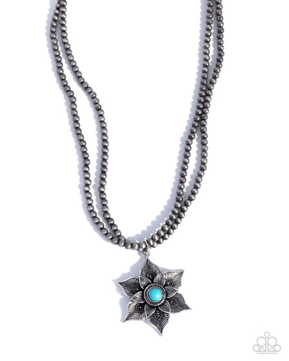 Necklace with star-shaped pendant featuring a blue gemstone on a white background